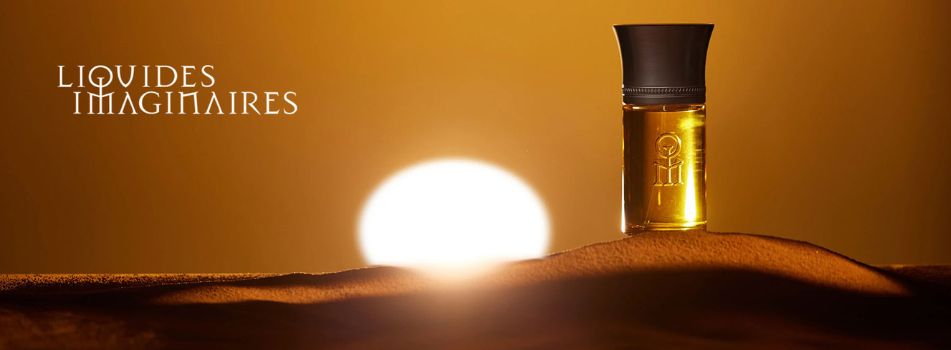 Werbebanner von Liquides Imaginaires: Ein goldener Parfumflakon steht auf einer sandigen Dünenlandschaft vor einem großen Sonnenuntergang, auf warmem goldbraunem Hintergrund. Links im Bild erscheint das Logo von Liquides Imaginaires.