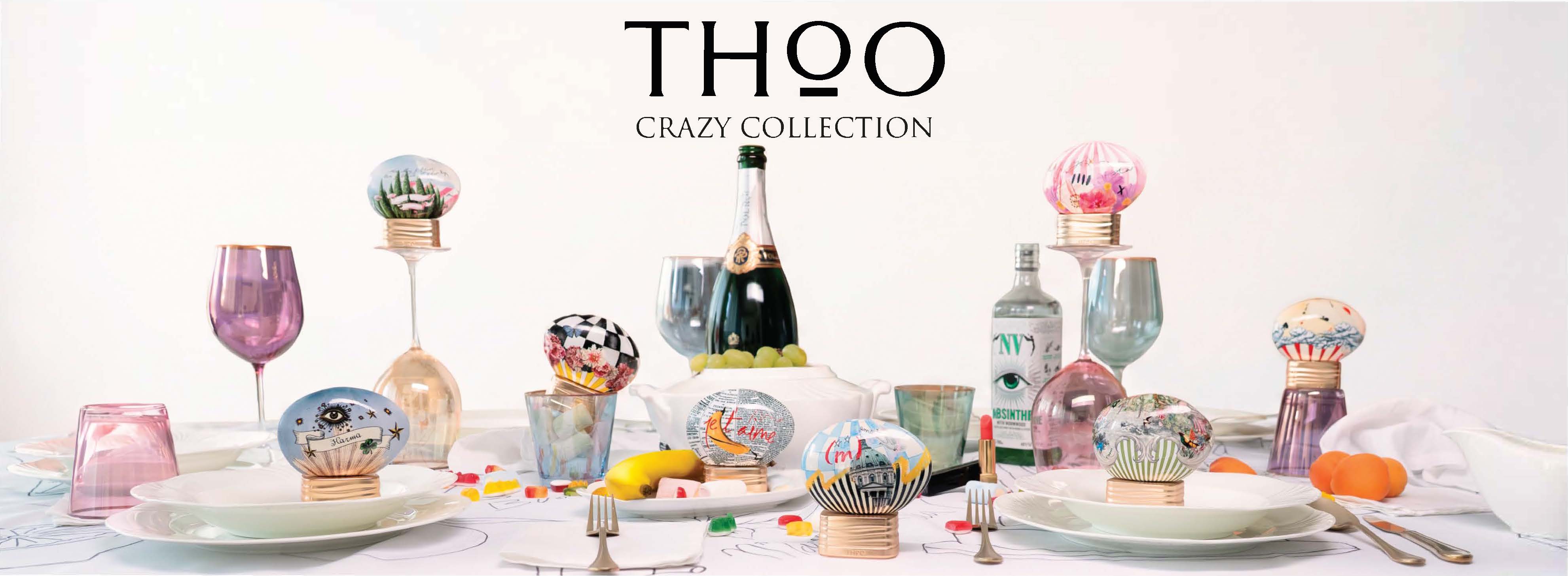 THoO Crazy Collection – Tischszene mit bunten THoO Parfümflakons in pilzförmiger Form mit farbenfrohen Illustrationen, dekorativen Weingläsern, Champagnerflasche, Süßigkeiten und Früchten auf einem gedeckten Tisch