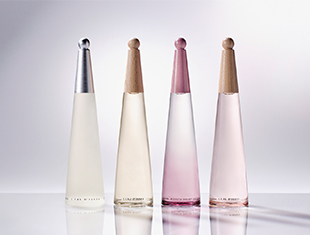 Vier elegante, konisch geformte Parfumflakons aus der 'L’Eau d’Issey'-Reihe von Issey Miyake stehen nebeneinander auf spiegelnder Fläche. Die Flakons sind in zarten Farbtönen gehalten: von transparent über cremefarben bis rosa, mit matten oder glänzenden Kappen in Silber oder Nude. Die Anordnung wirkt stilvoll, minimalistisch und modern.