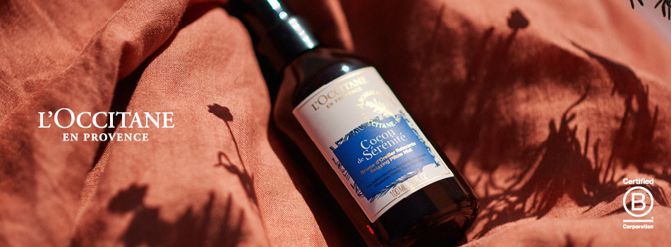 L'OCCITANE Lavendel-Spray auf weichem Stoff mit warmem Licht.