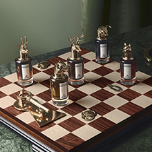 Mehrere Parfumflaschen aus der Penhaligon’s Portraits Kollektion stehen auf einem Schachbrett. Die Flakons tragen auffällige, goldene Verschlüsse in Tierform wie Hirsch, Hund oder Fasan.