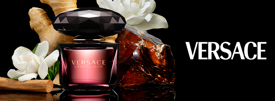 Werbebild des Parfums 'Versace Crystal Noir'. Der Flakon ist dunkel und elegant, mit einem facettierten, schwarzen Verschluss und roséfarbenem Verlauf. Umgeben ist er von weißen Blüten, Ingwer, Zimtstangen und einem großen Bernsteinstück. Rechts steht das Versace-Logo in weißer Schrift auf schwarzem Hintergrund.